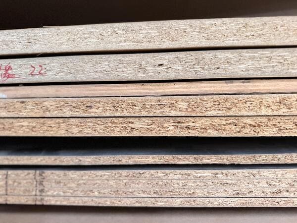 Exposed edges of several particleboard panels showing differences in particle distribution and core appearance