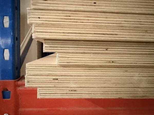 Close-up of stacked plywood panels showing the layered veneer core and panel edges.
