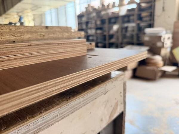 Stacked plywood panels with visible veneer layers in a cabinet workshop