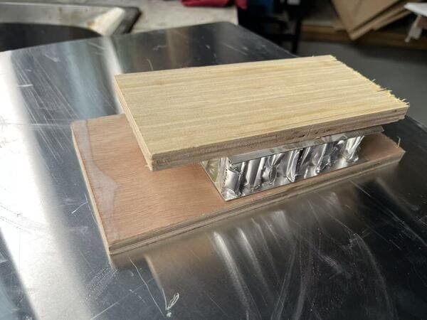 Factory sample showing an aluminum honeycomb core between plywood layers during composite panel bonding.