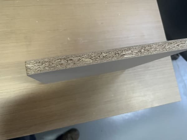 Close-up of a melamine-faced OSB panel edge showing the wood strand core