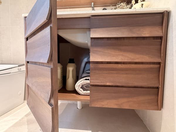 Walnut veneer bathroom vanity with shaped cabinet fronts in a residential model home