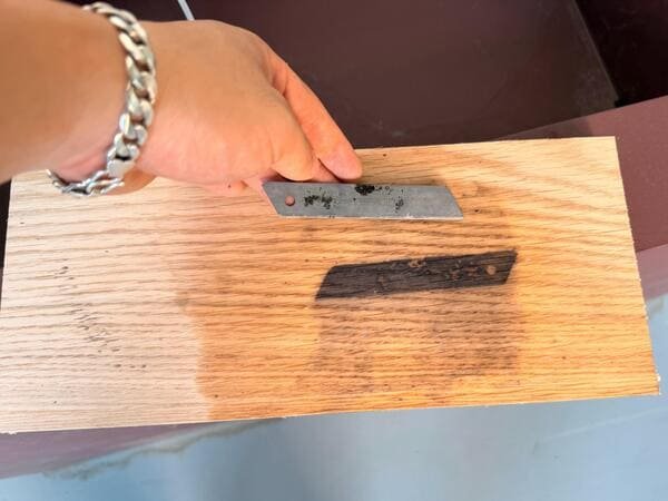 Blue-black iron stain on wet white oak veneer after contact with a steel utility knife blade.